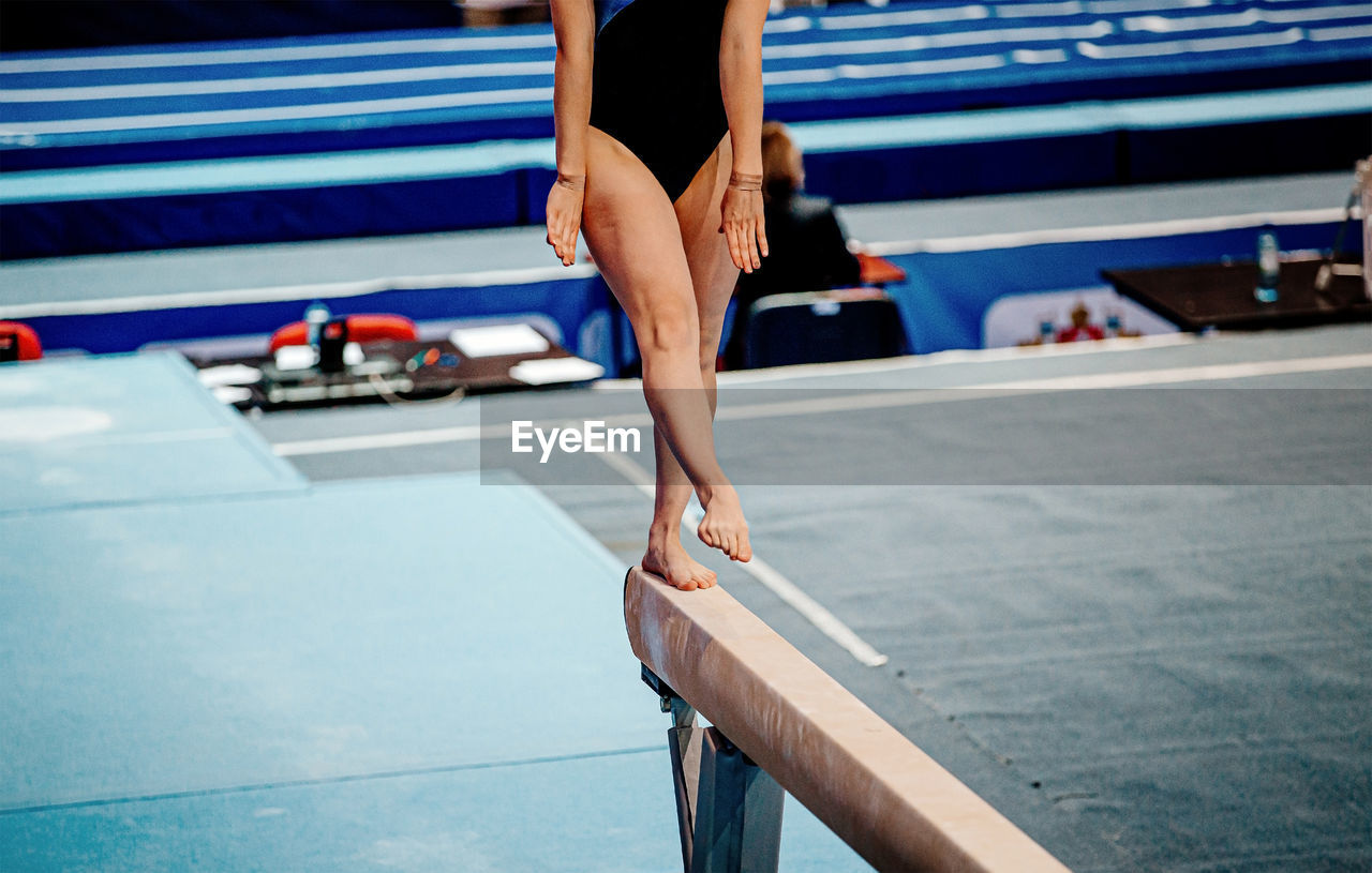 Low section of gymnast standing on wooden plank