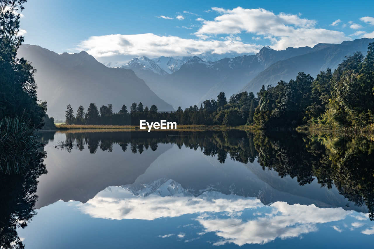 Scenic view of lake and mountains against sky with reflections at lake matheson, new zealand