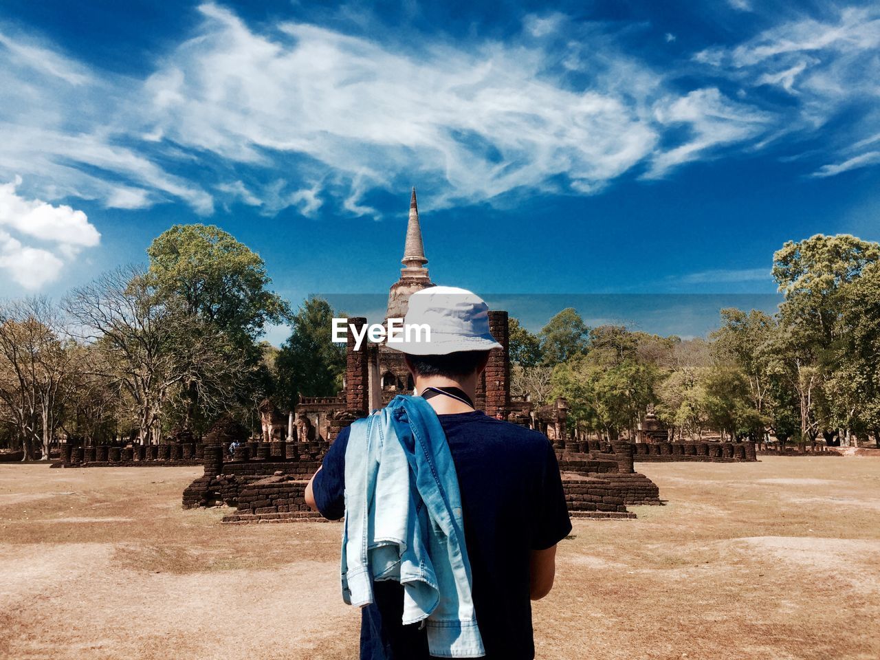 Rear view of man standing by wat chong lom at sukhothai historical park