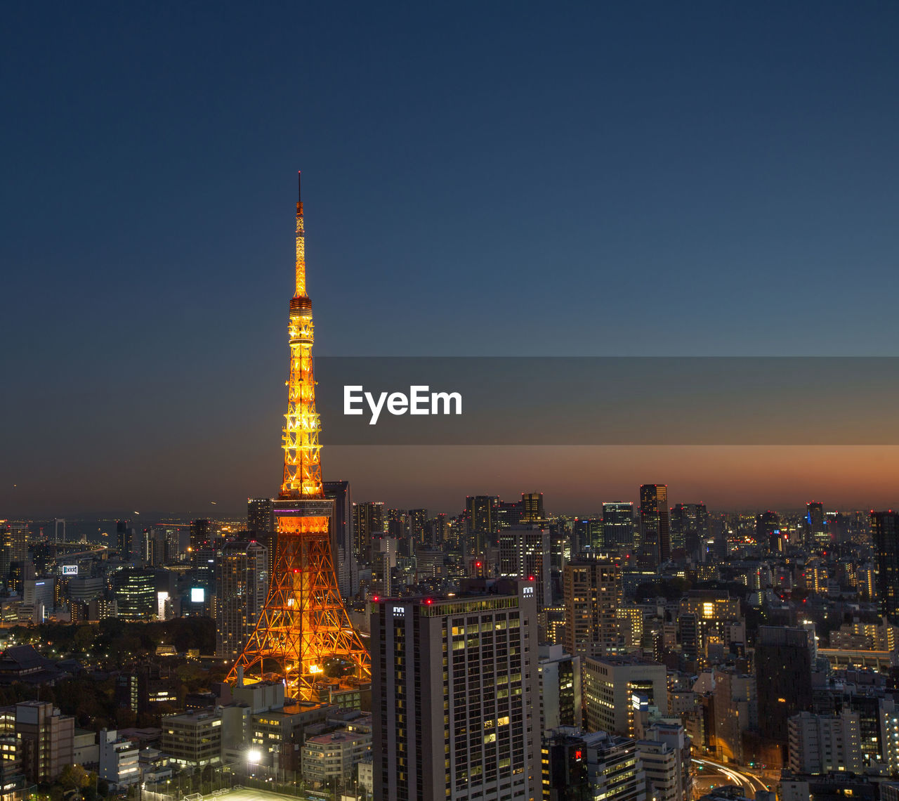 Illuminated tokyo tower and city against clear sky at dusk