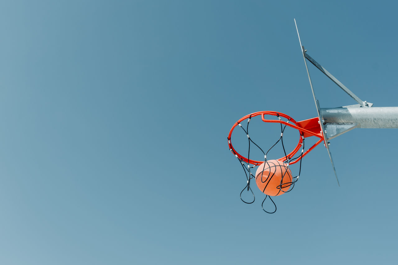 LOW ANGLE VIEW OF BASKETBALL HOOP AGAINST CLEAR BLUE SKY