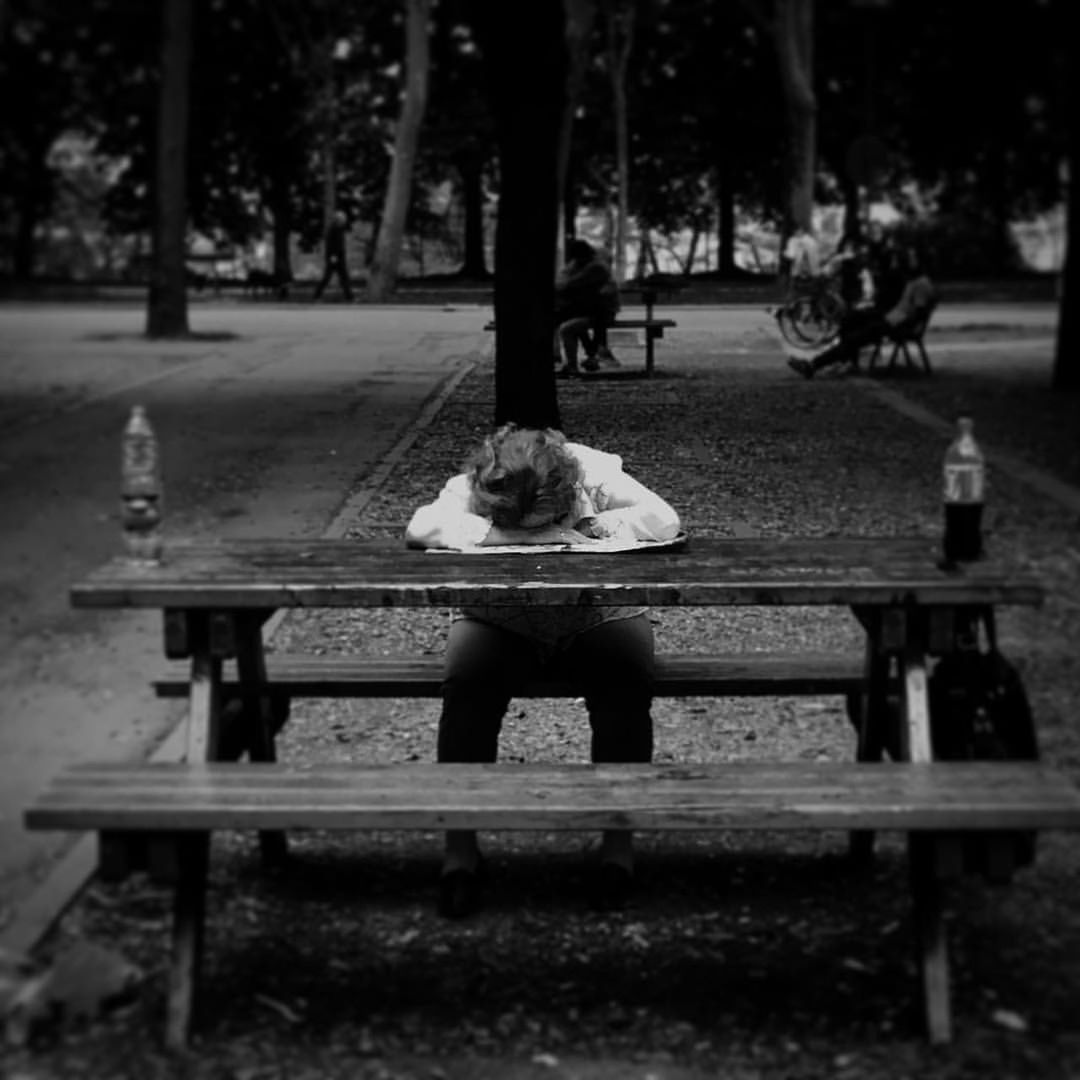 Woman leaning on table while sitting on bench at park