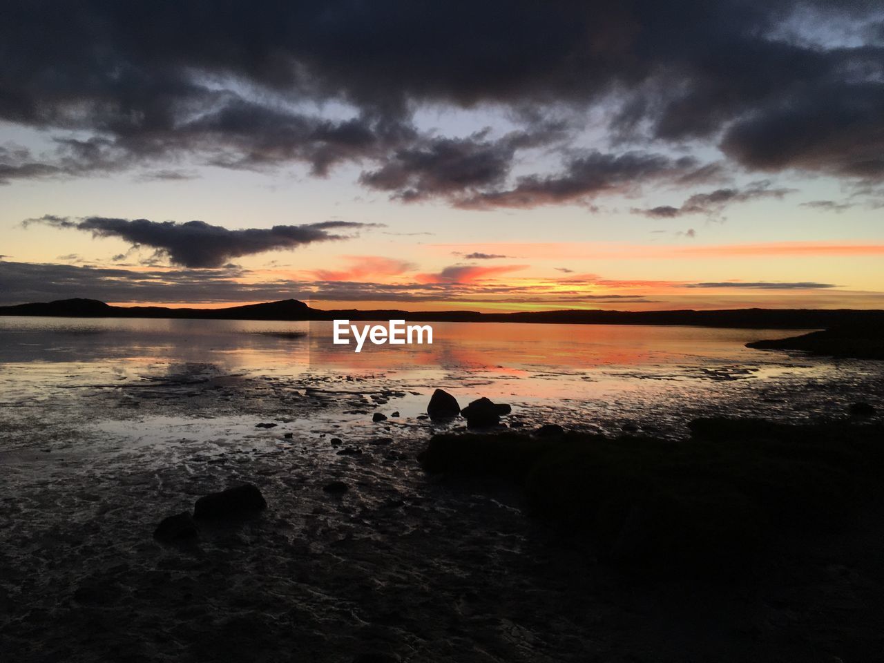 SCENIC VIEW OF BEACH AGAINST DRAMATIC SKY