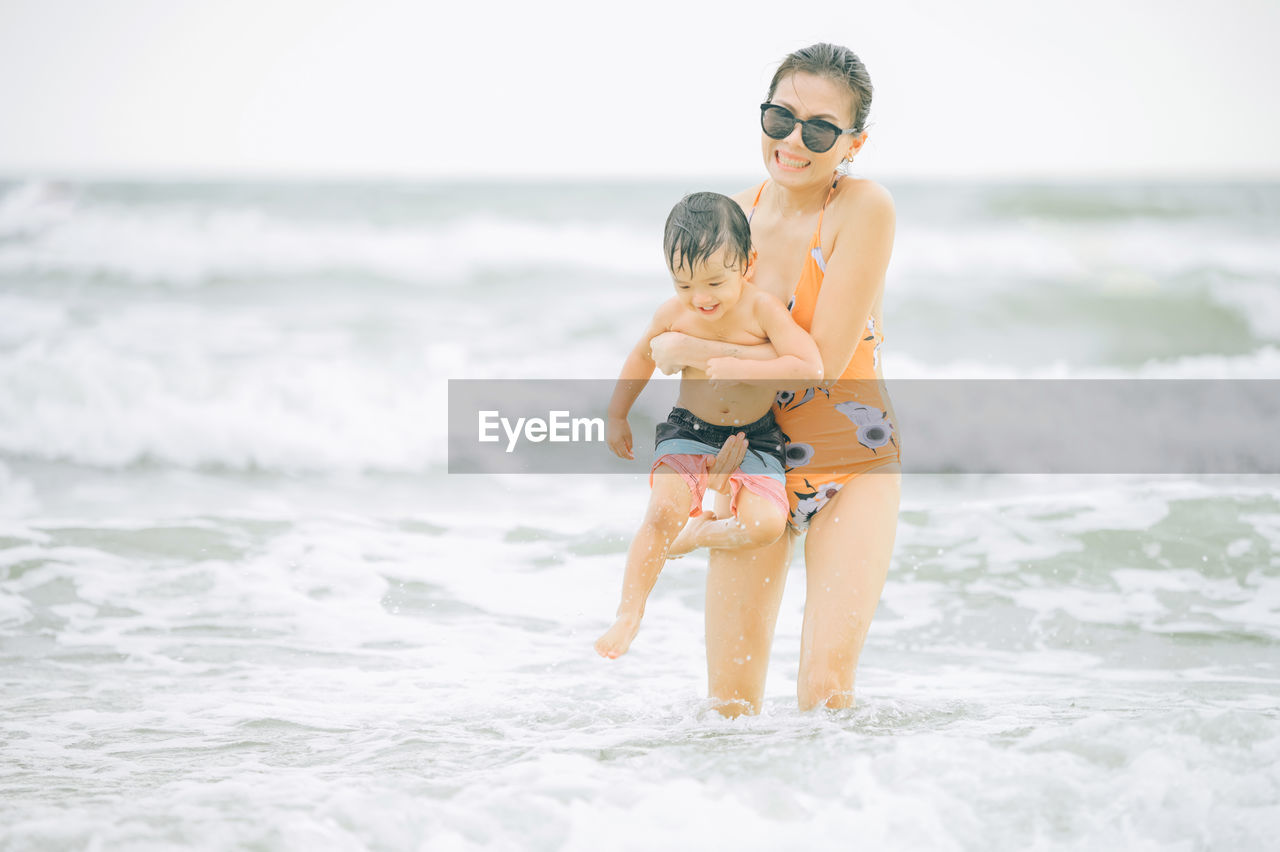 Smiling mother with son enjoying on sea water