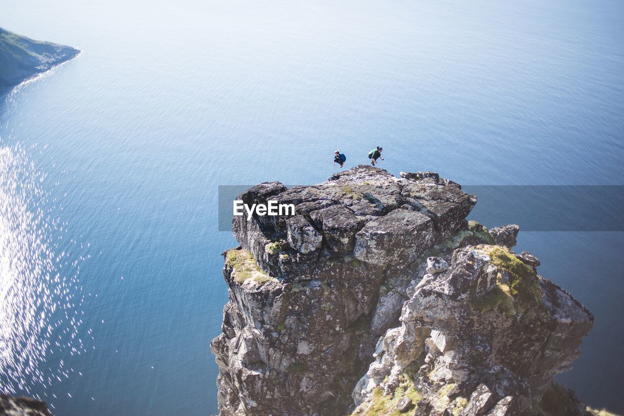 High angle view of man and woman jumping on cliff