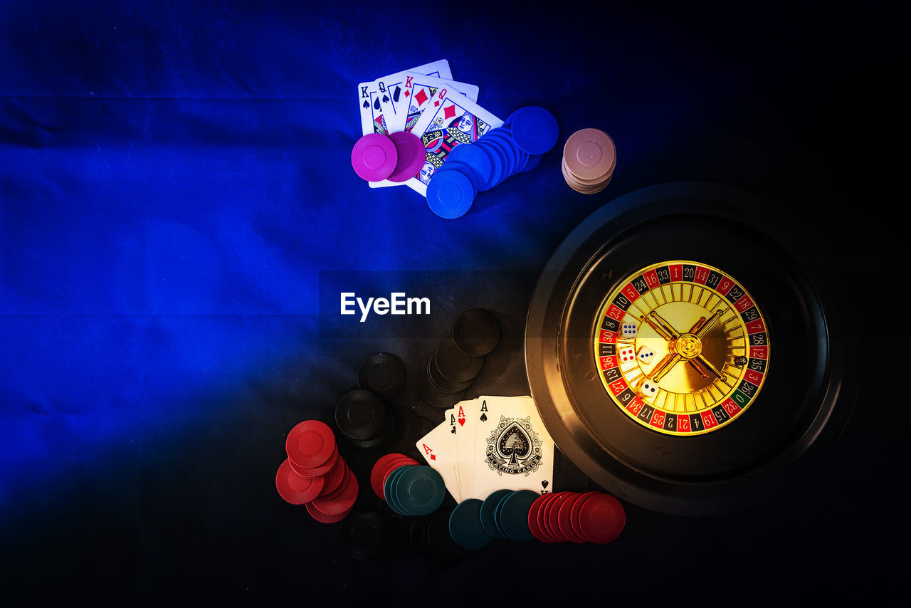 High angle view of roulette wheel with gambling chips and cards on table