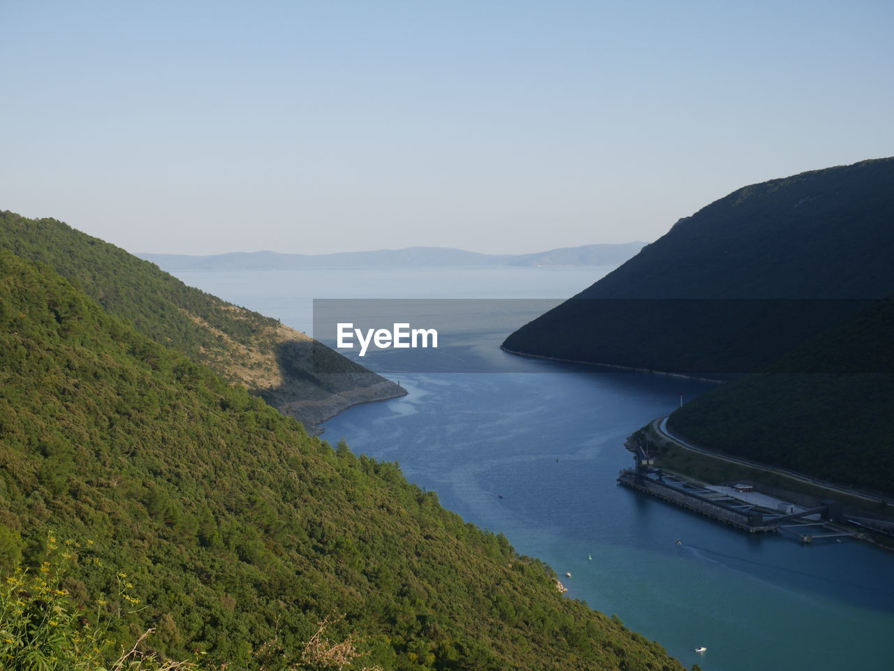 Scenic view of sea and mountains against clear sky