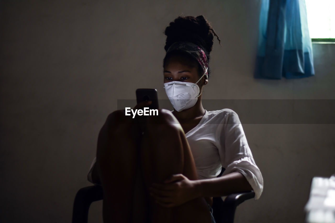 Young woman in face mask using smartphone