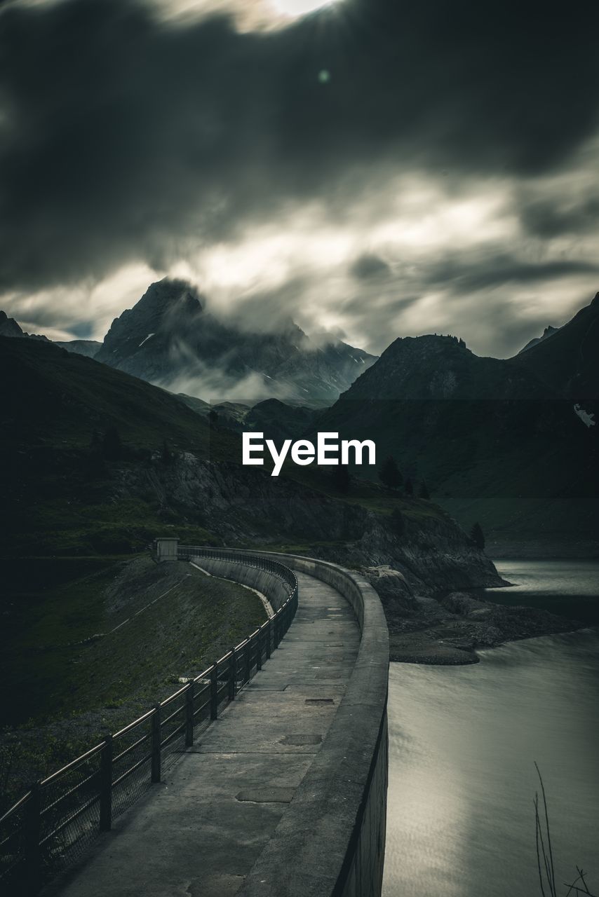 Empty road leading towards mountains against sky