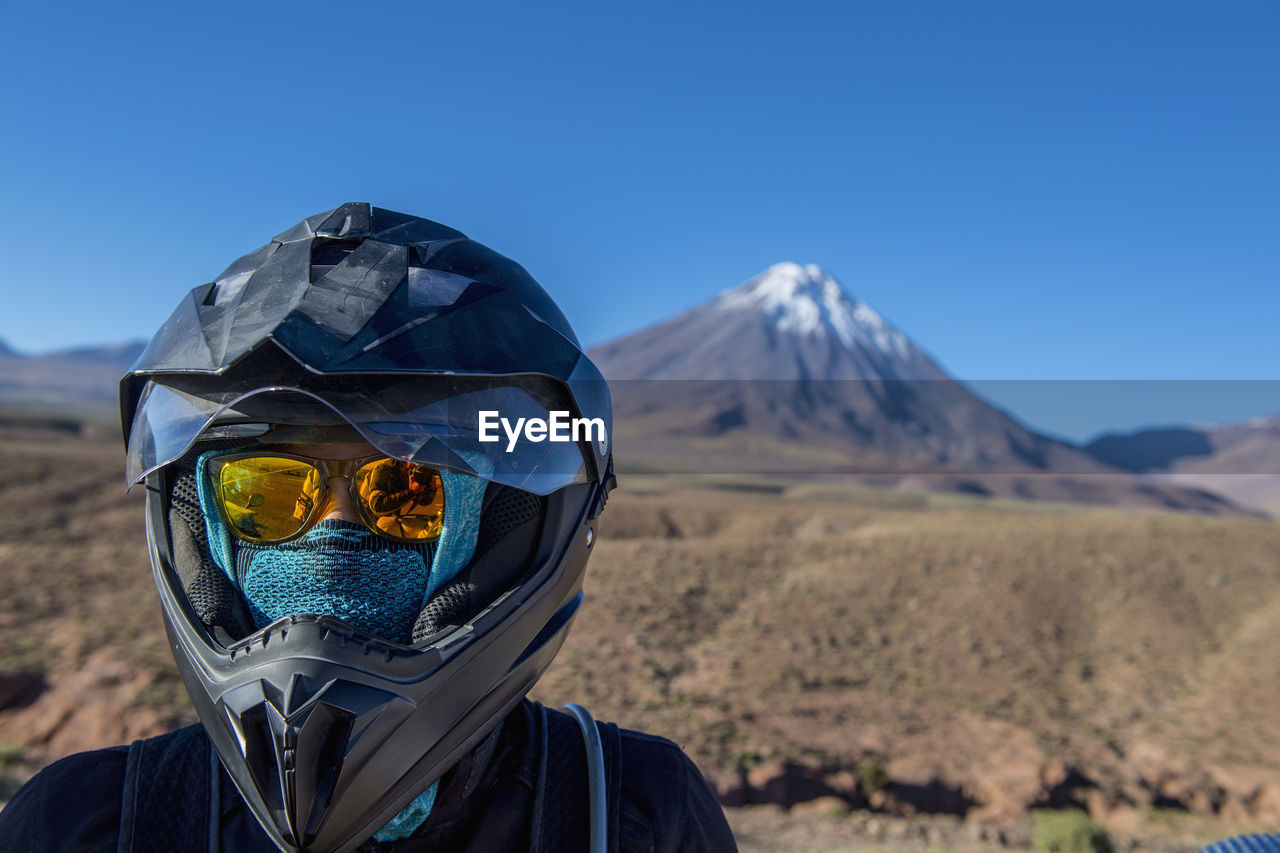 Woman with motorbike helmet, in front of the stratovolcano licancabur