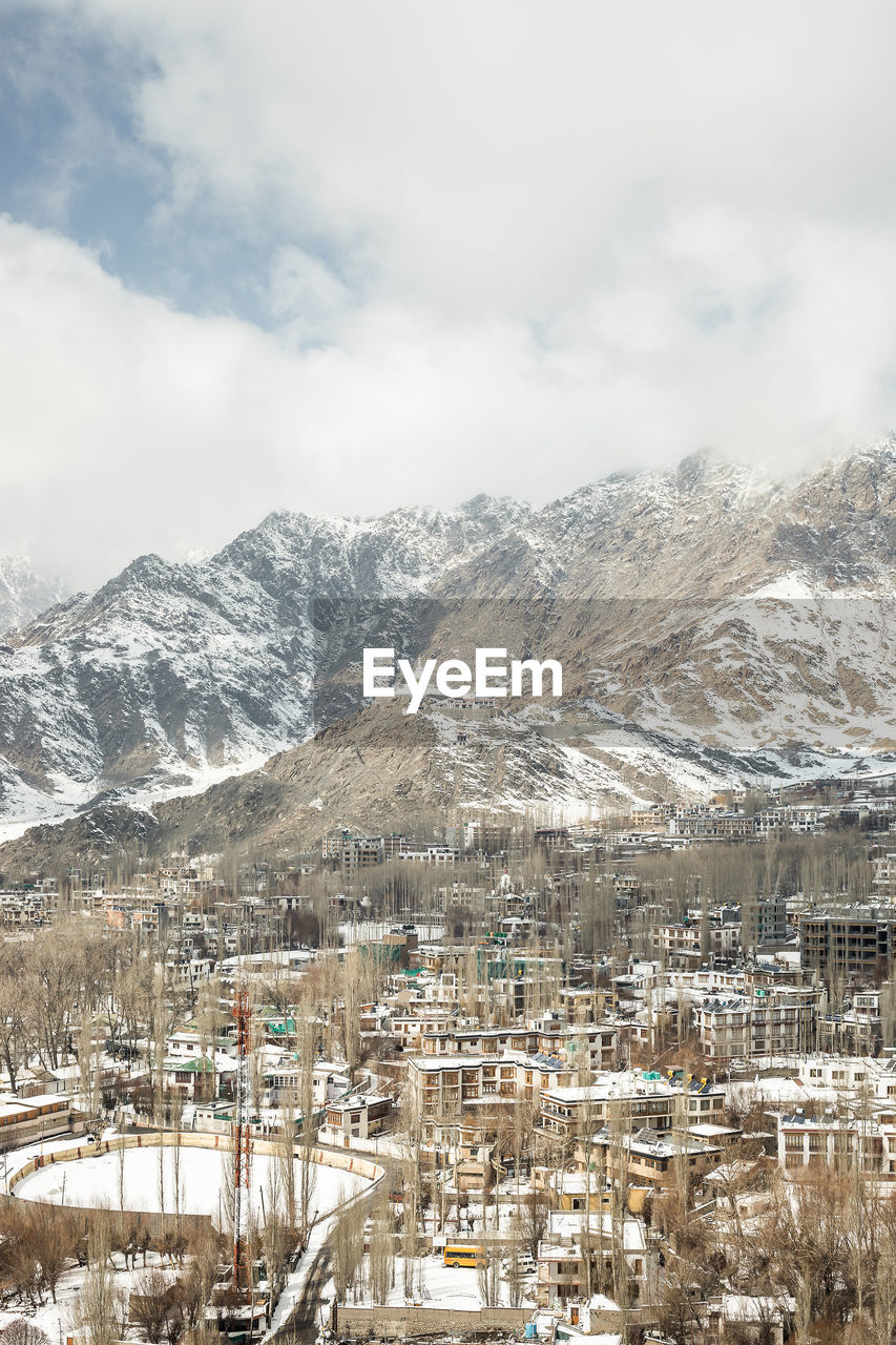 AERIAL VIEW OF TOWNSCAPE AND MOUNTAINS AGAINST SKY