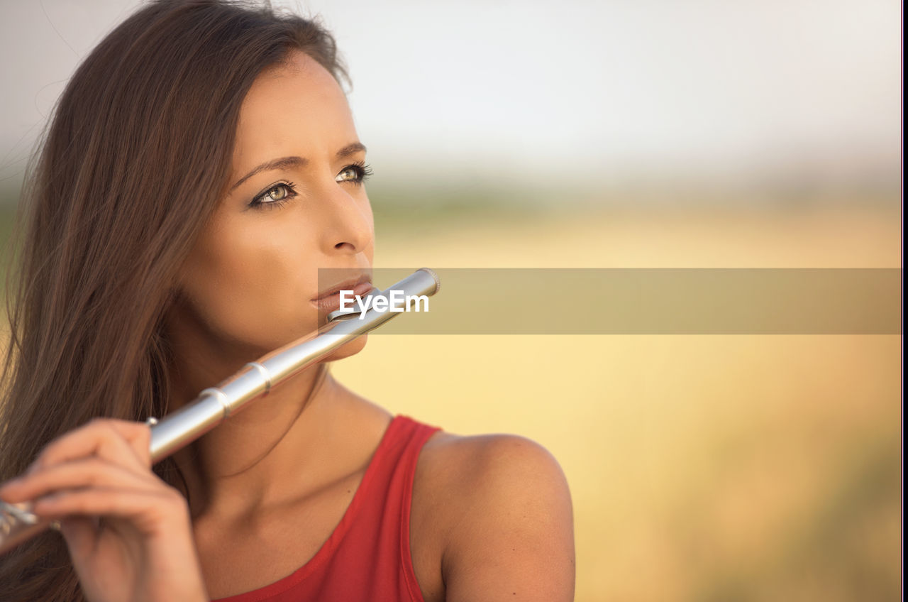 Close-up of beautiful woman playing flute outdoors