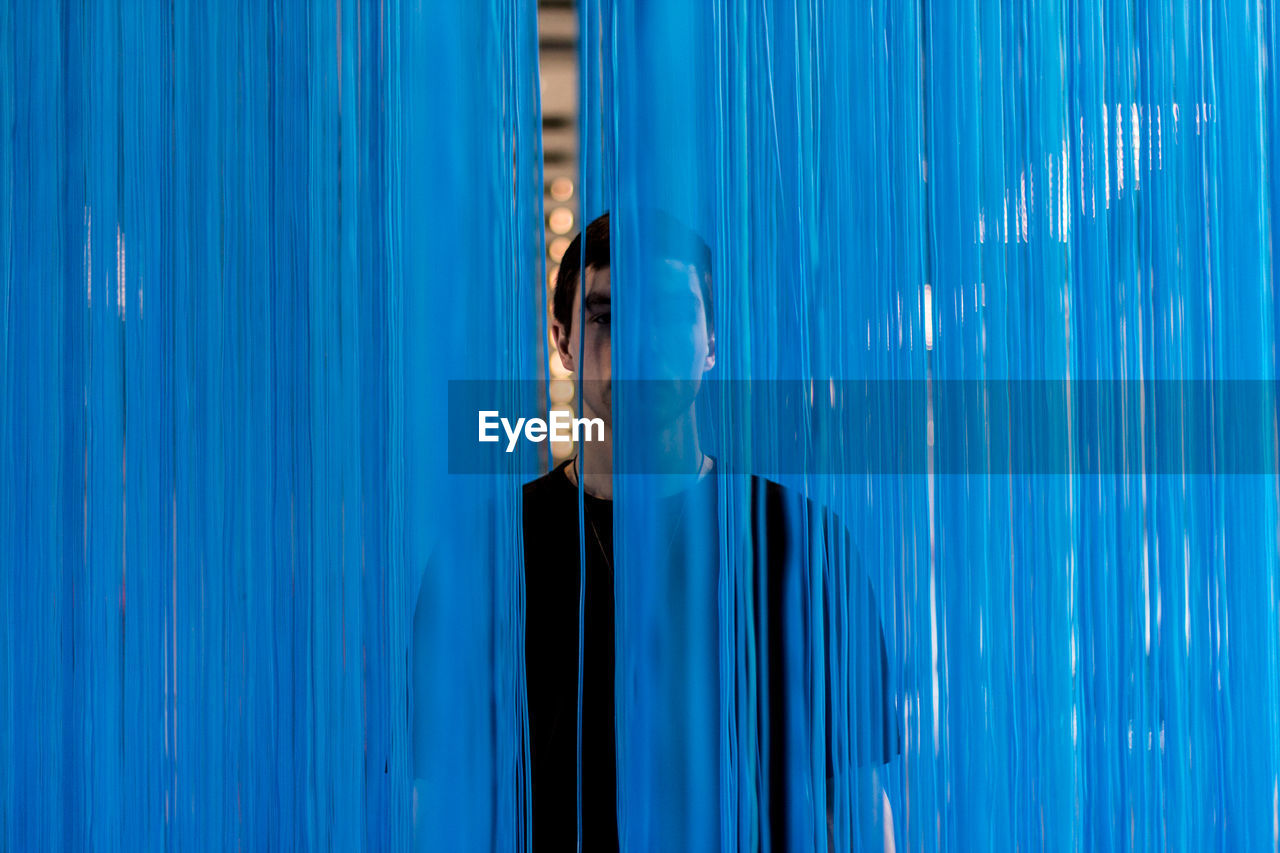 Portrait of man standing behind blue textile