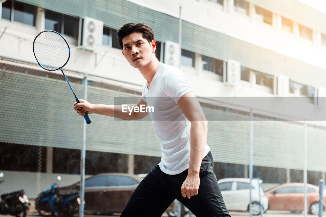Confident man playing with racket in city