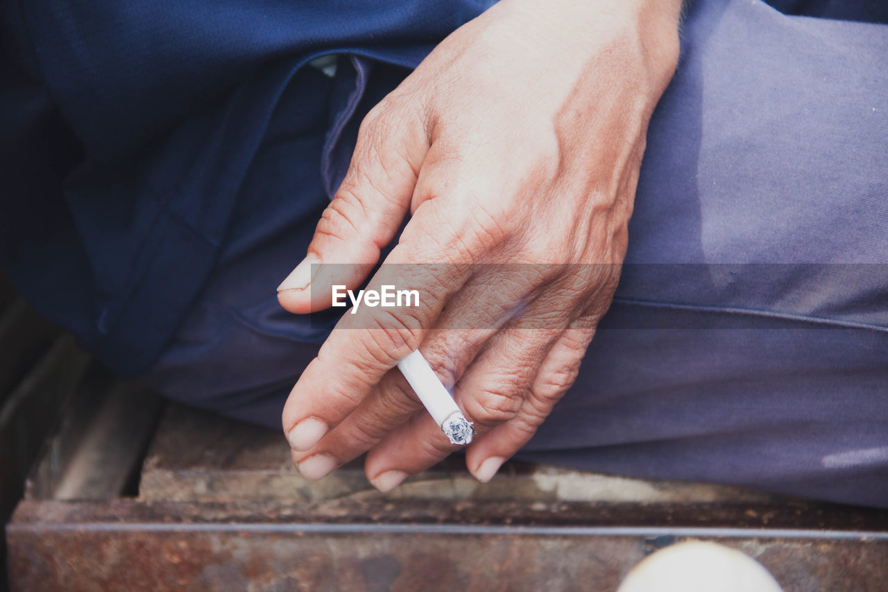 MIDSECTION OF MAN HOLDING CIGARETTE