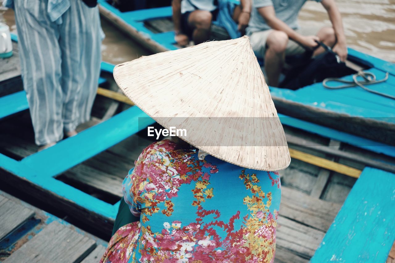 Rear view of woman wearing asian style conical hat in boat