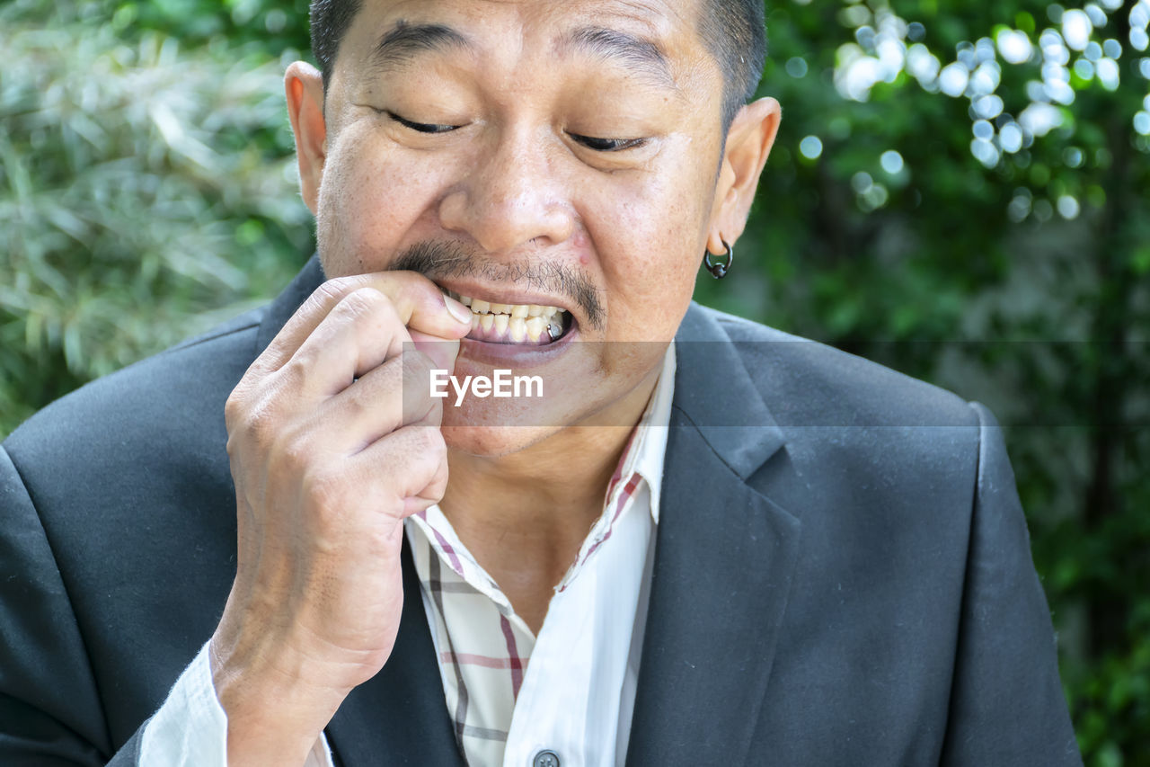 Portrait of man biting nails outdoors