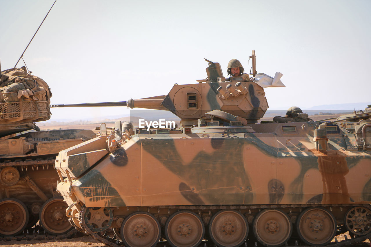 Man in armor tank on land against sky
