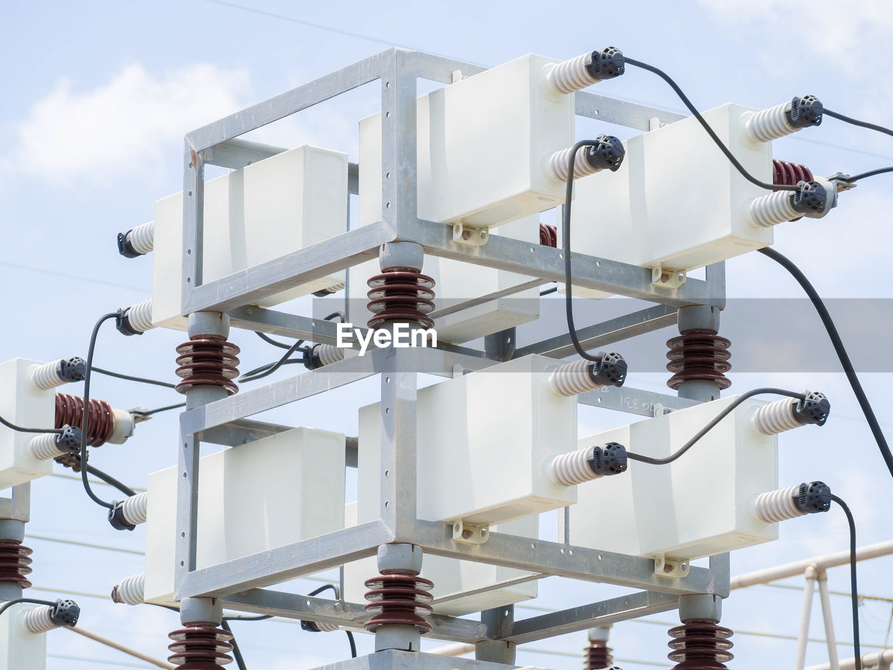 Low angle view of electrical equipment against sky