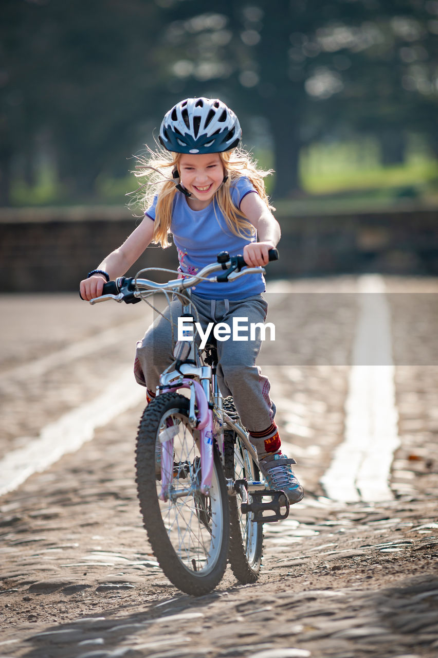Cheerful girl riding bicycle on land