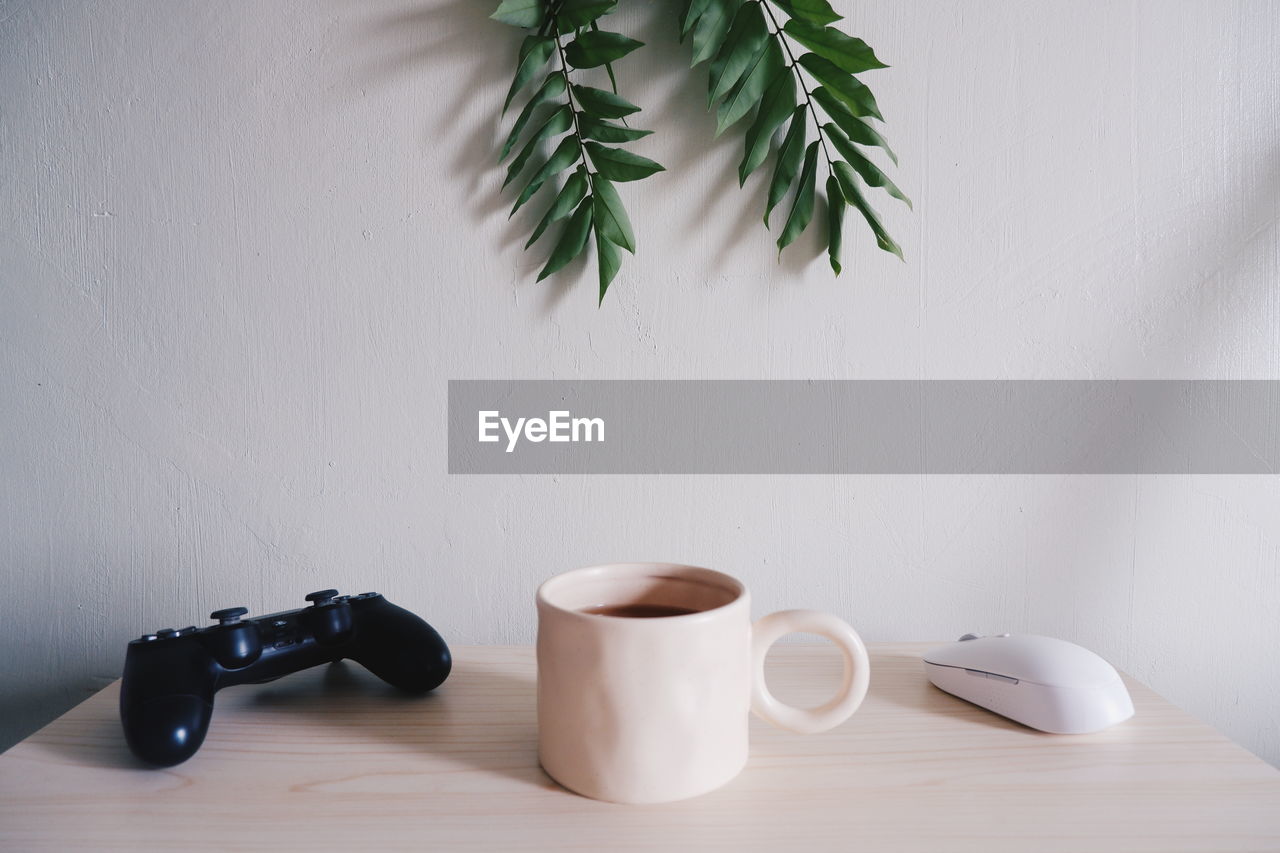 Close-up of coffee cup on table against wall