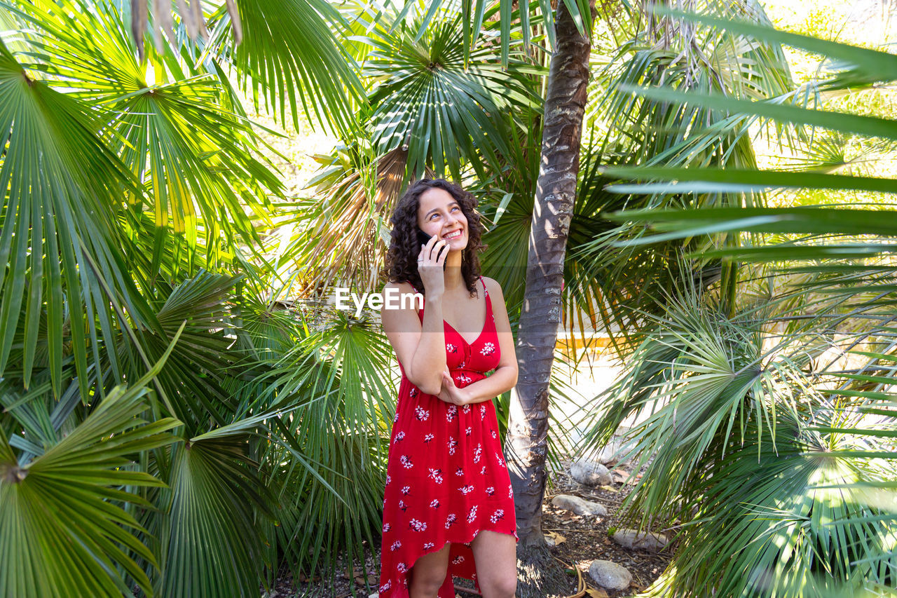 portrait of young woman standing amidst palm tree