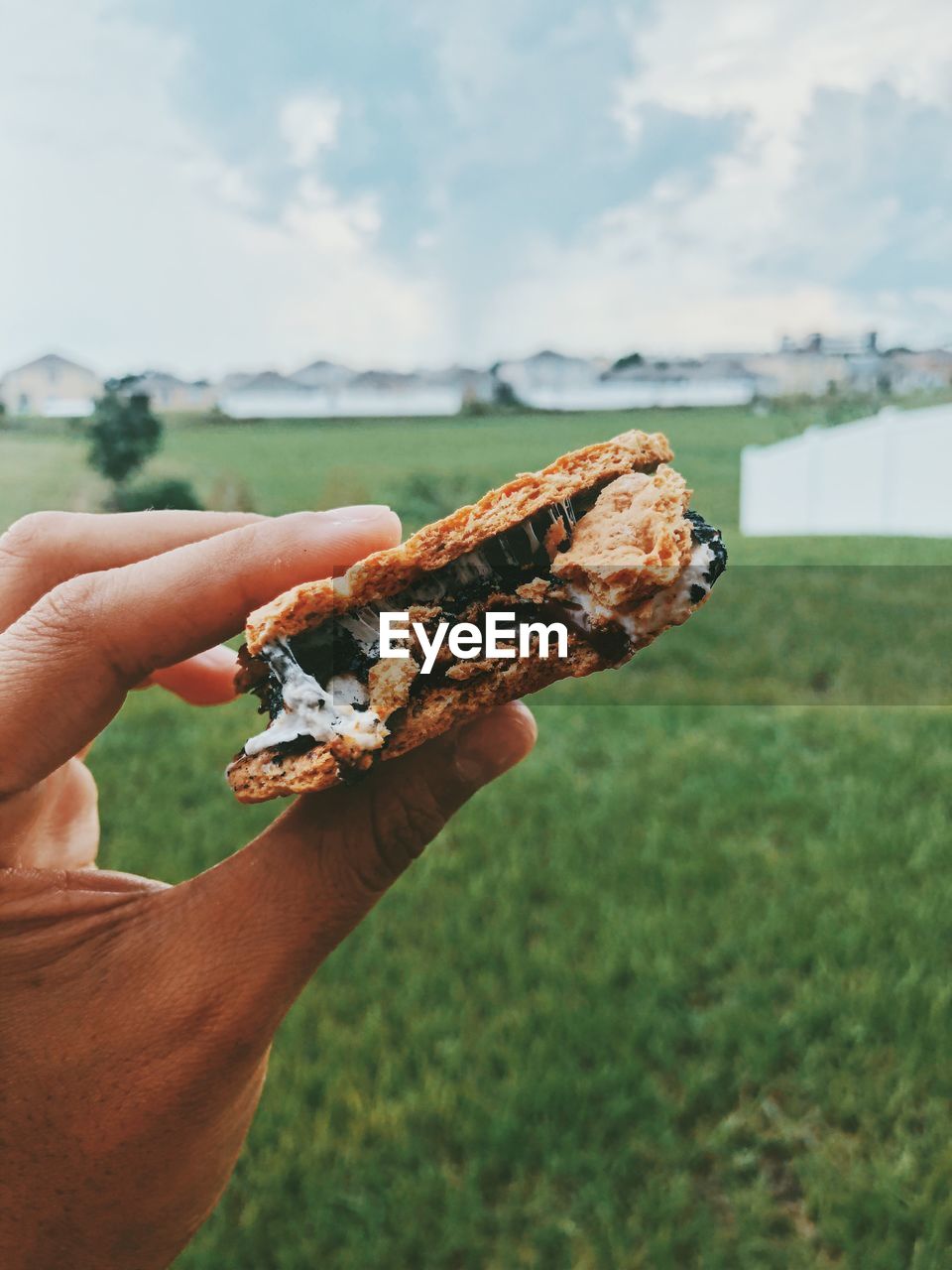 Close-up of hand holding crackers with chocolate and marshmallow outdoors