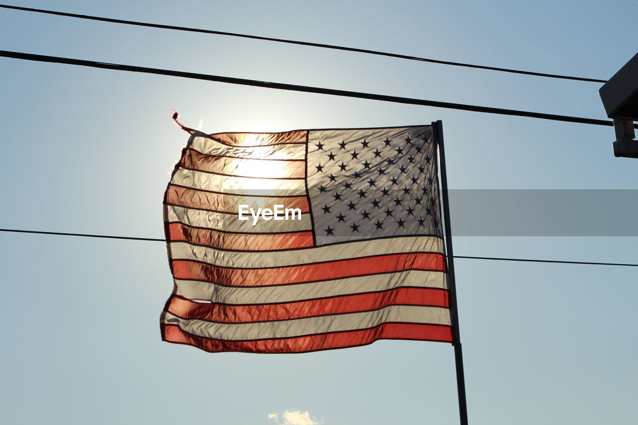 Low angle view of flags hanging on pole against blue sky