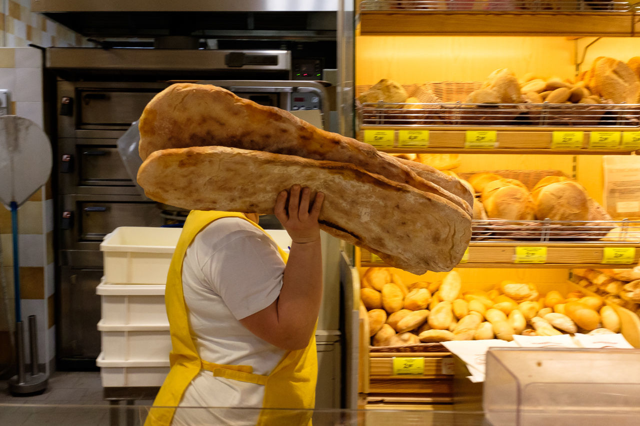 Side view of person holding breads against shelf in store