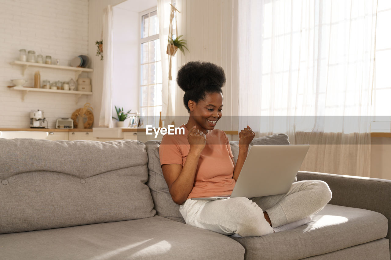 Young woman using laptop while sitting on sofa