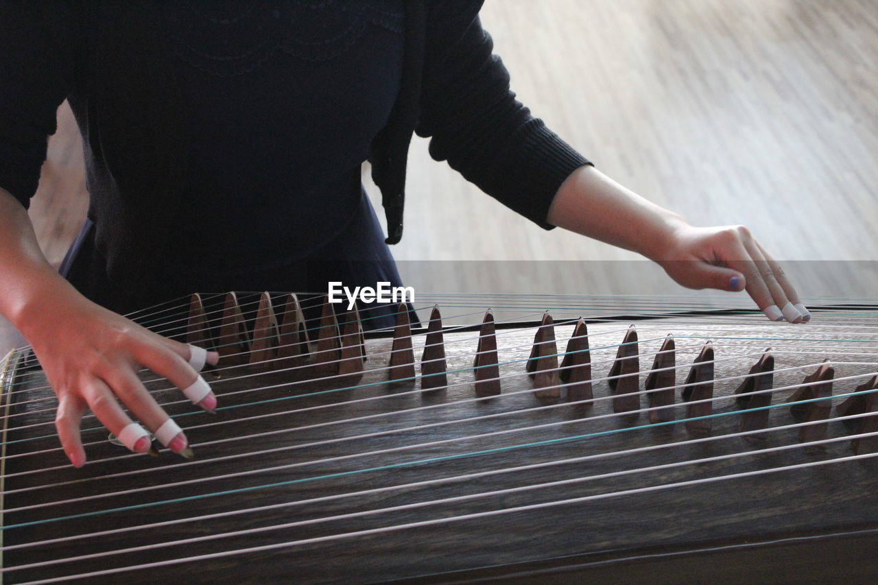 Woman playing guzheng indoors