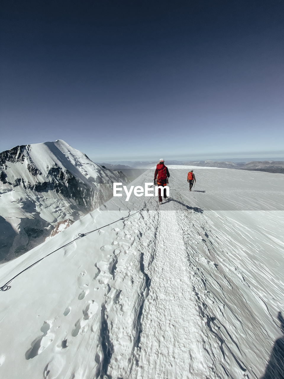 Roped party descending mont blanc under dark blue sky during high wind