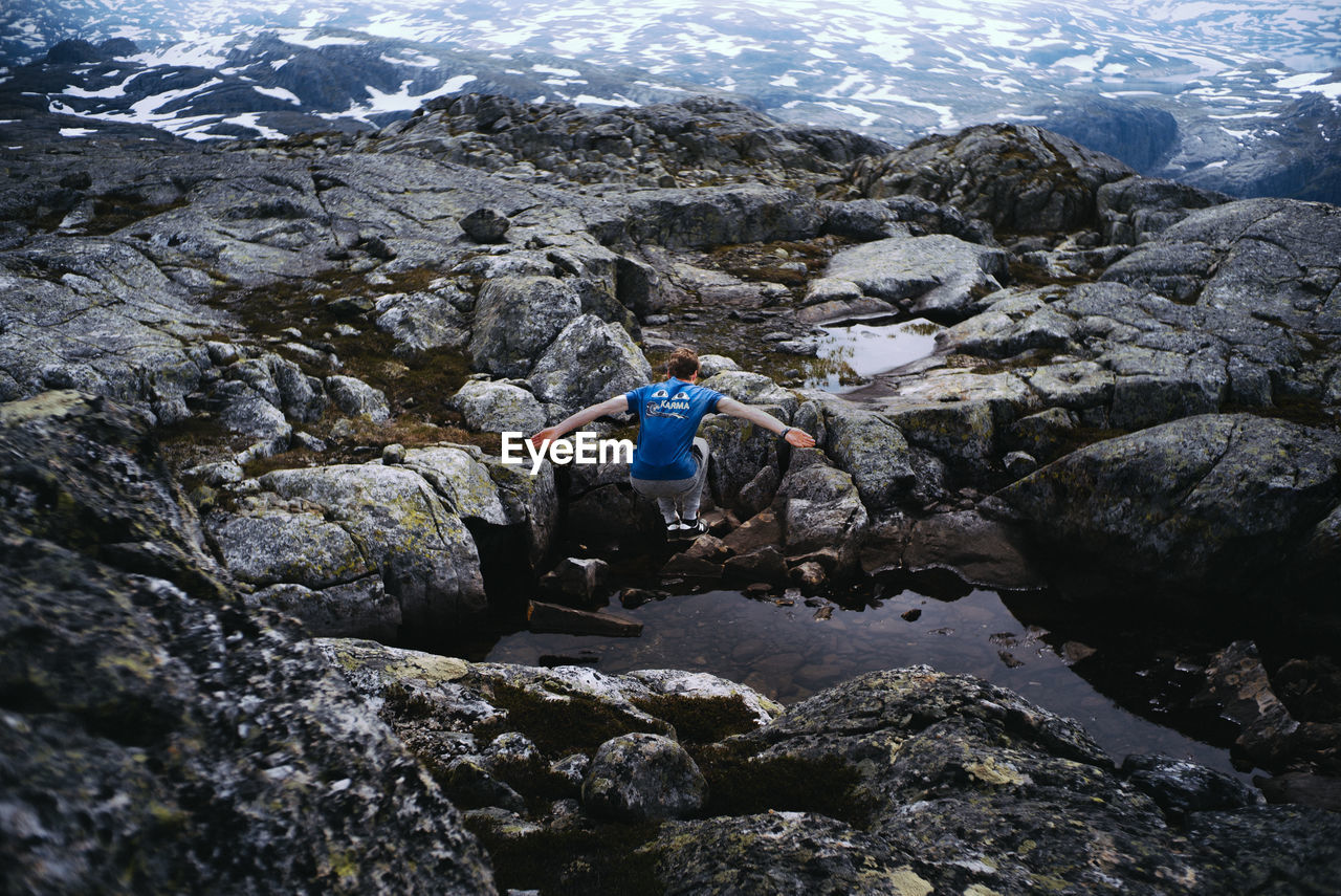 REAR VIEW OF WOMAN ON ROCKS