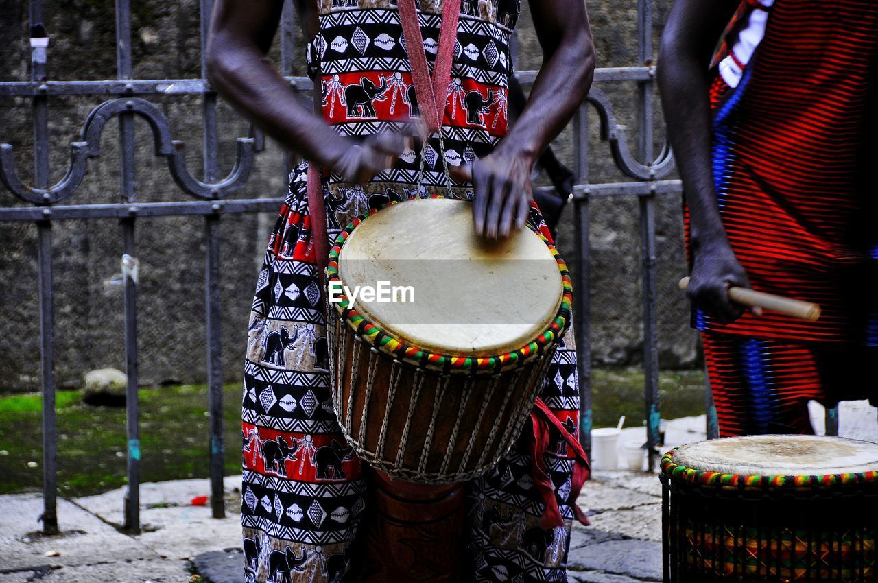 Midsection of street performers playing bongo