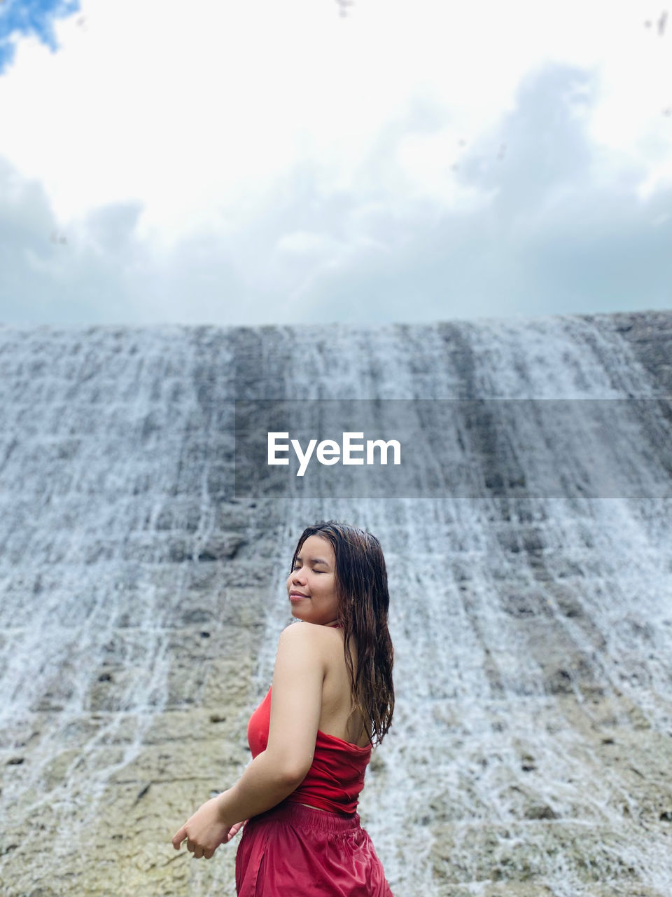 side view of young woman standing at beach against sky