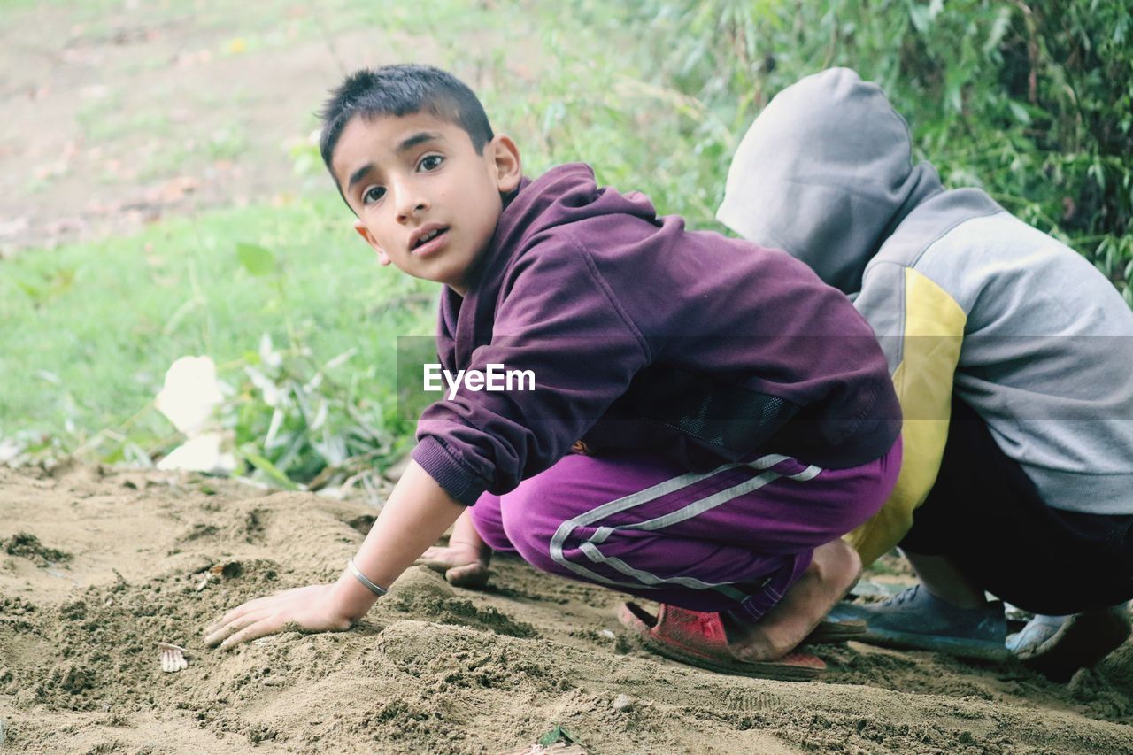 Portrait of boy with friend crouching on land