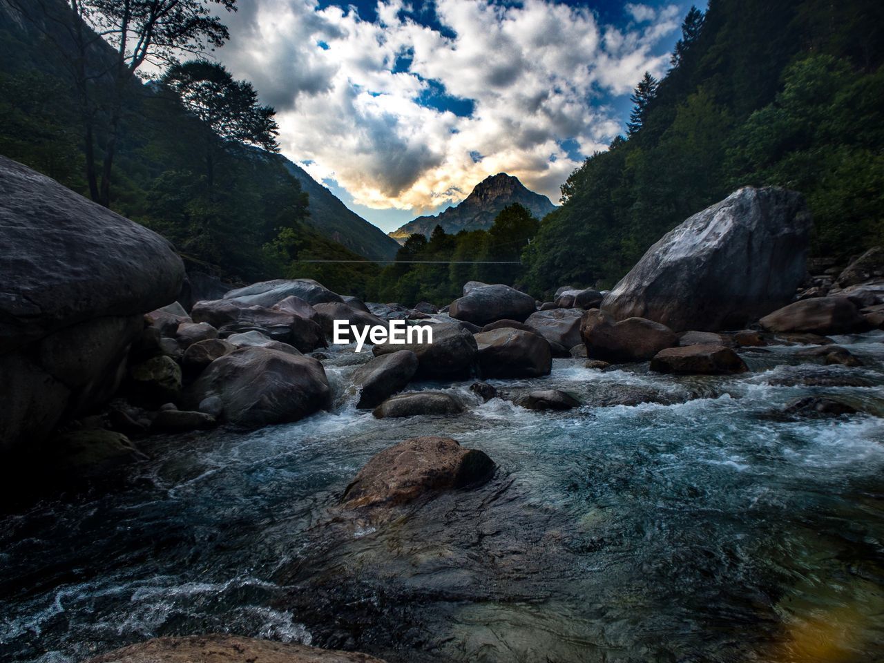 River flowing through rocks against sky