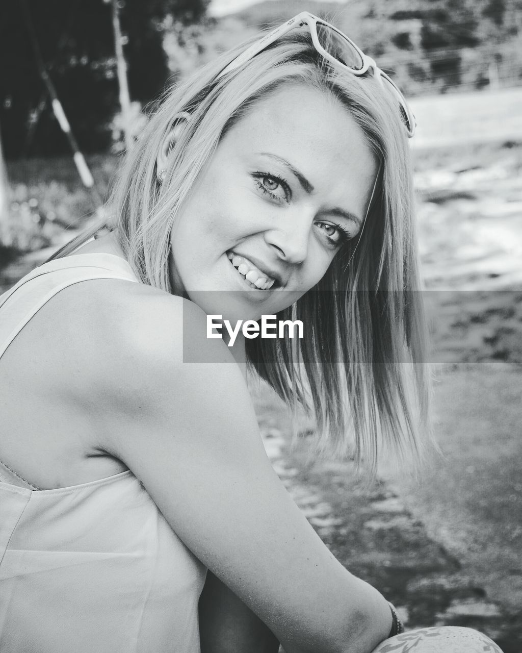 Portrait of happy young woman sitting at park