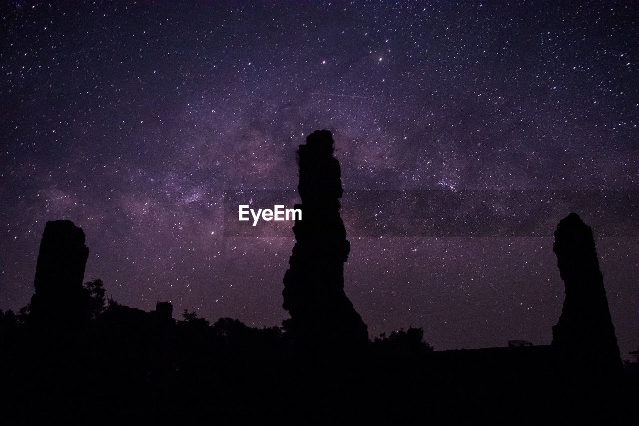 Silhouette rock formations against sky at night