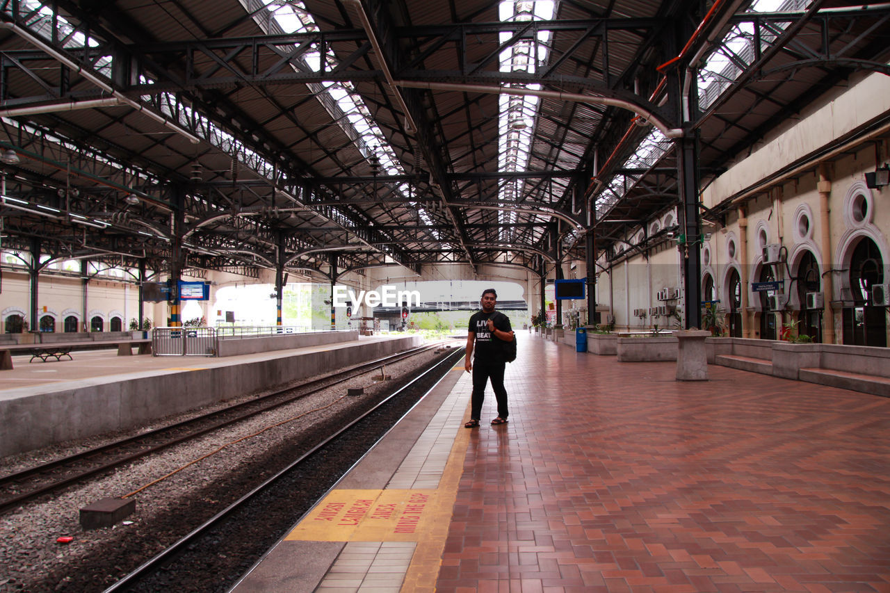 Man standing at railroad station platform