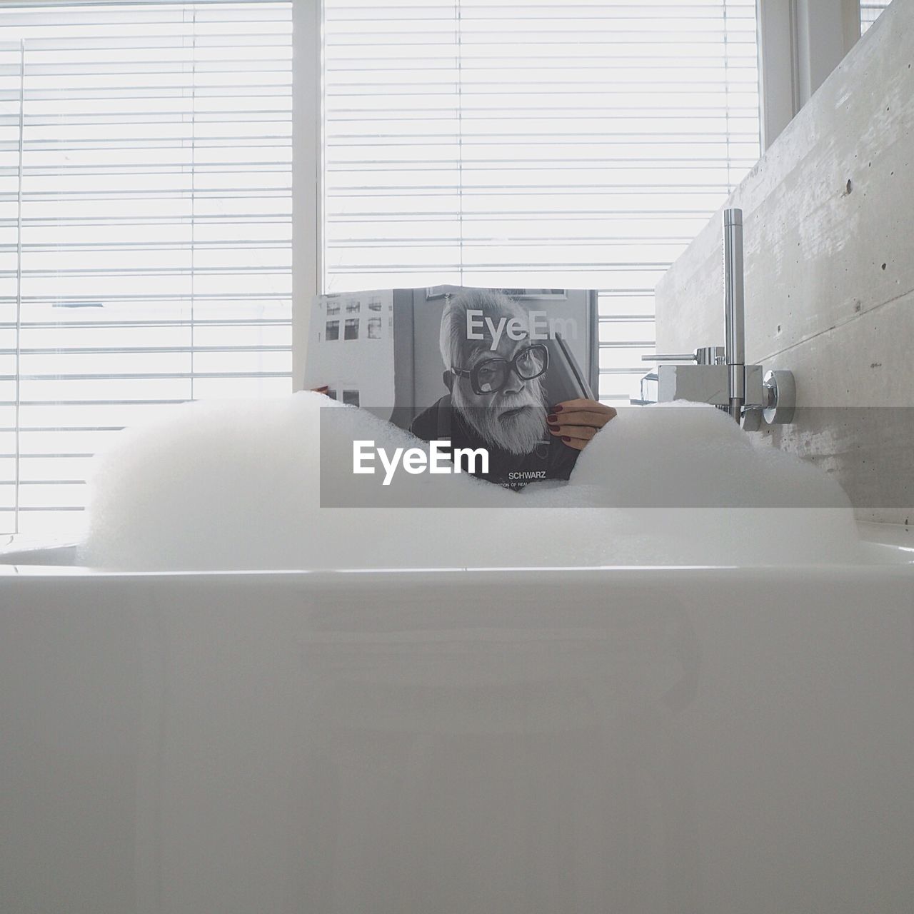 Woman holding magazine in bathtub at home