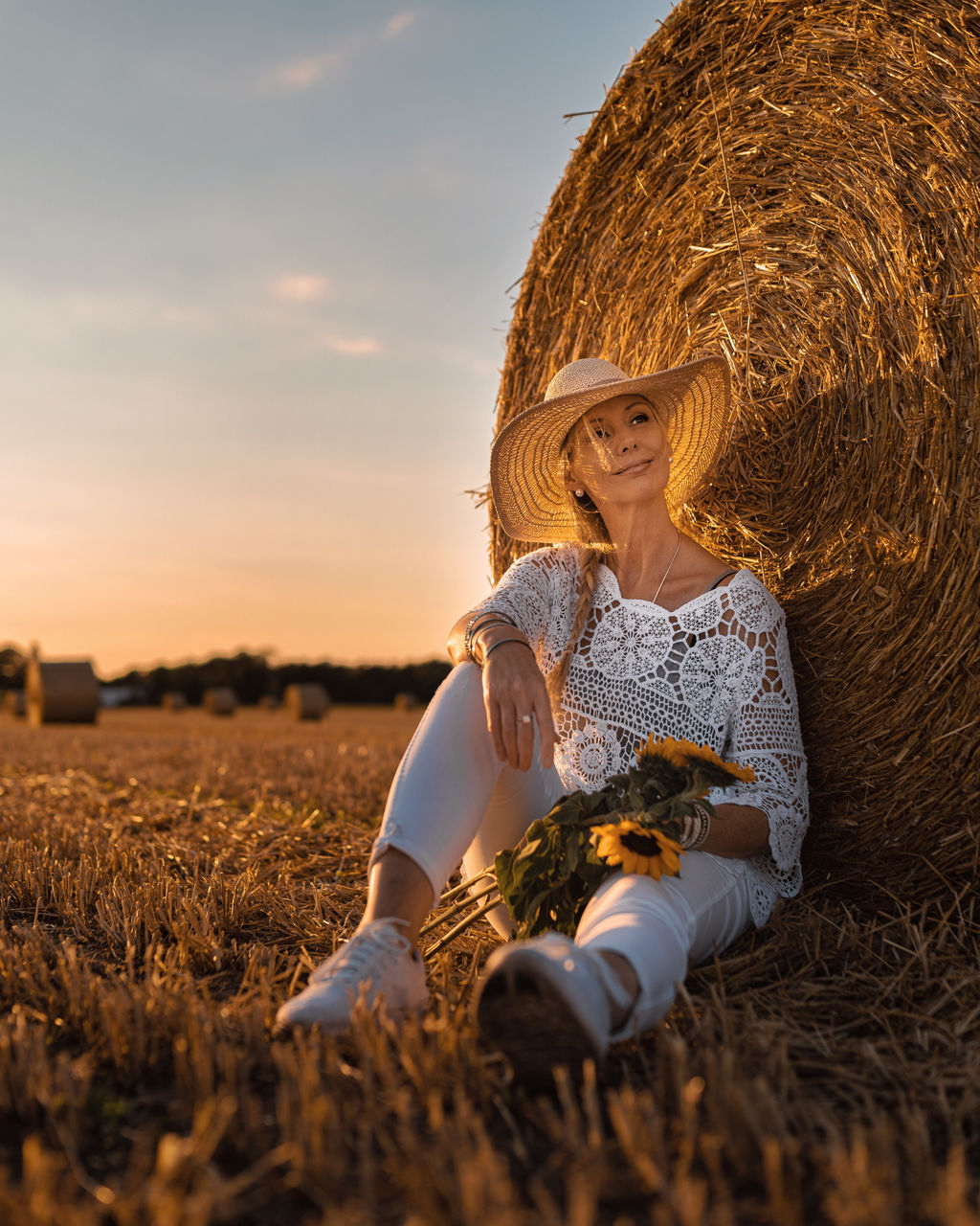Woman wearing straw hat sitting on field