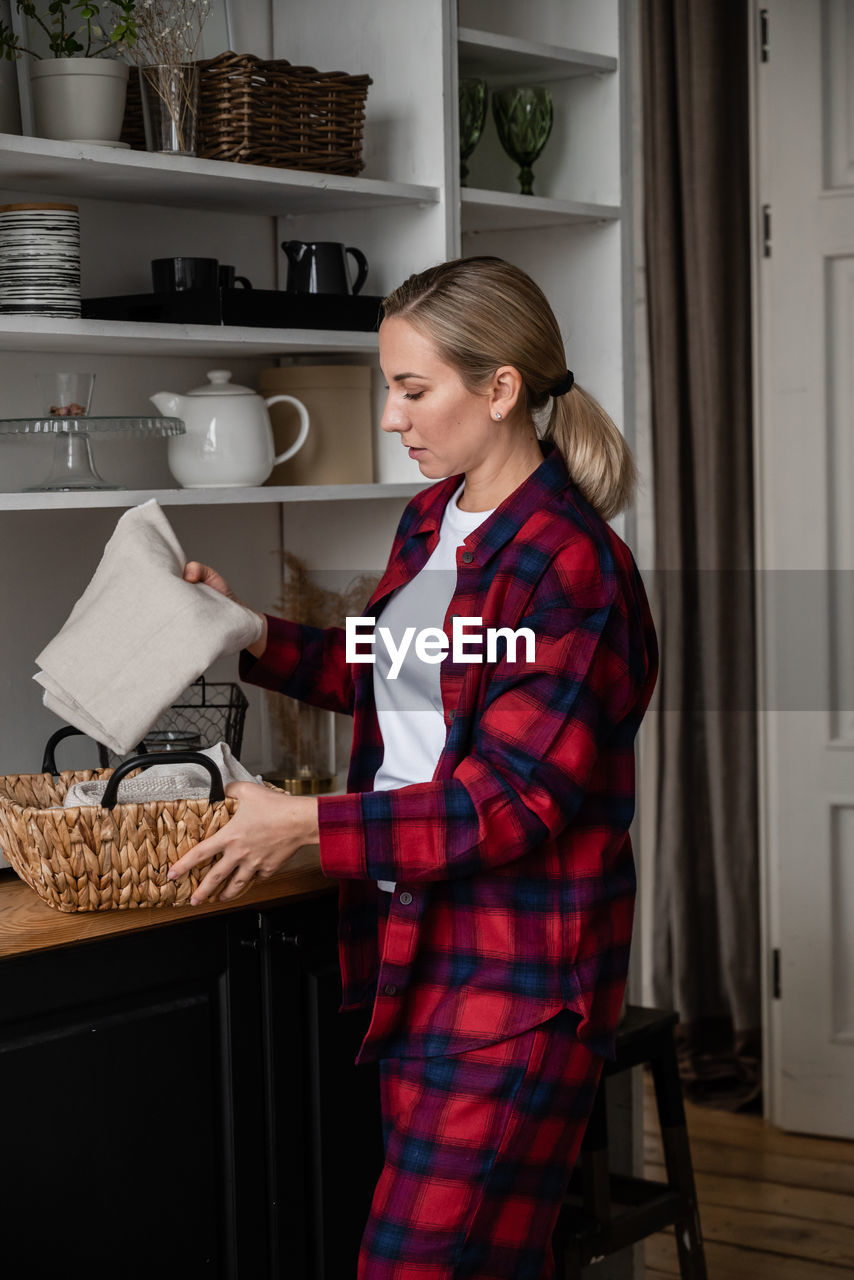 An attractive young blonde tidies up and organizes things in her cozy kitchen. home style concept