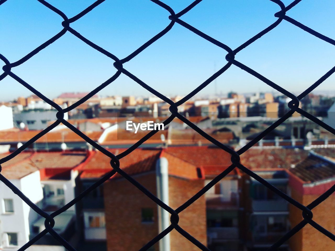FULL FRAME SHOT OF CHAINLINK FENCE AGAINST BUILDINGS