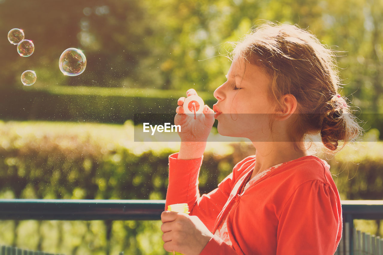 Close-up of girl blowing bubbles at park