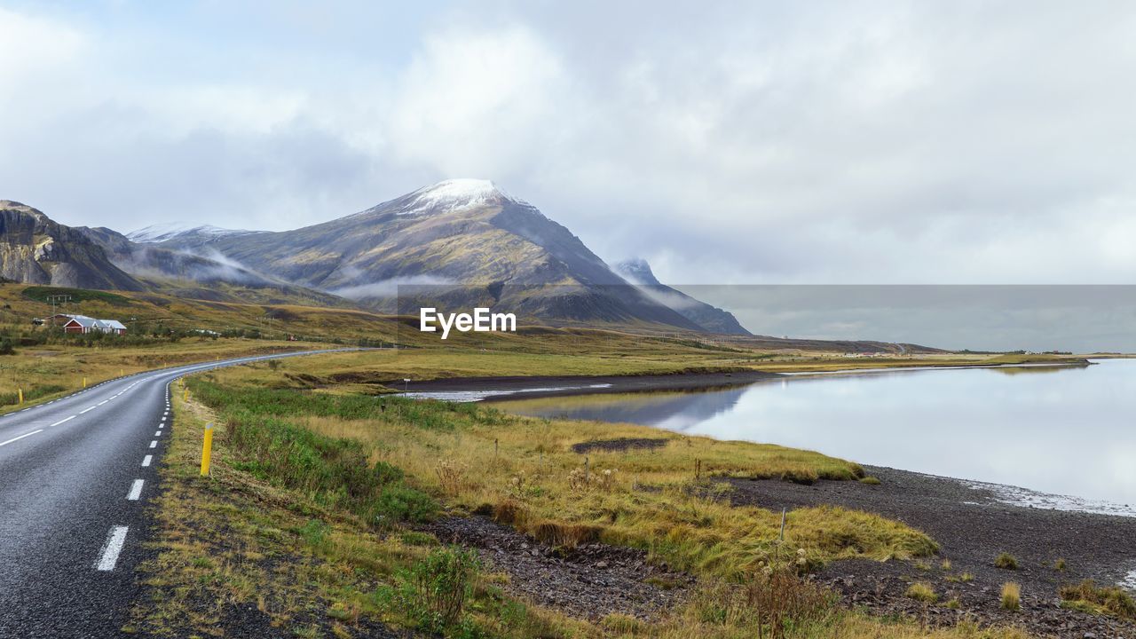 Scenic view of road by mountains against sky