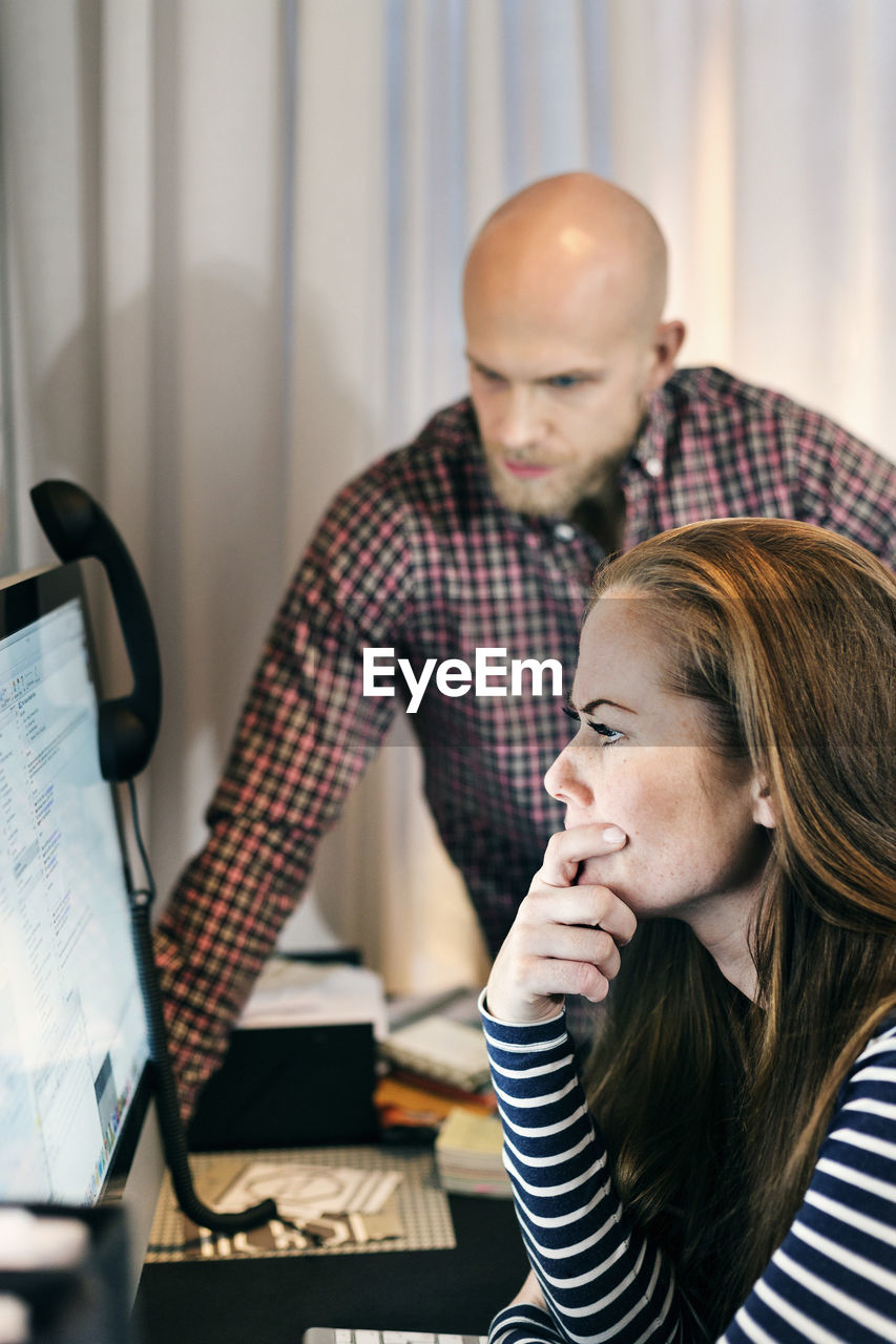 Business people looking at computer in office