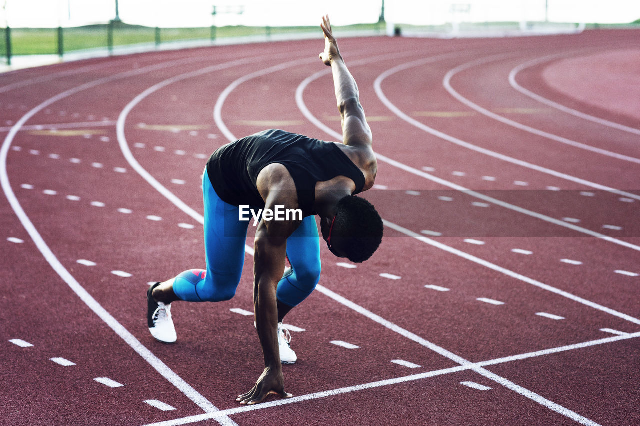 Determined sportsman at starting block on running tracks