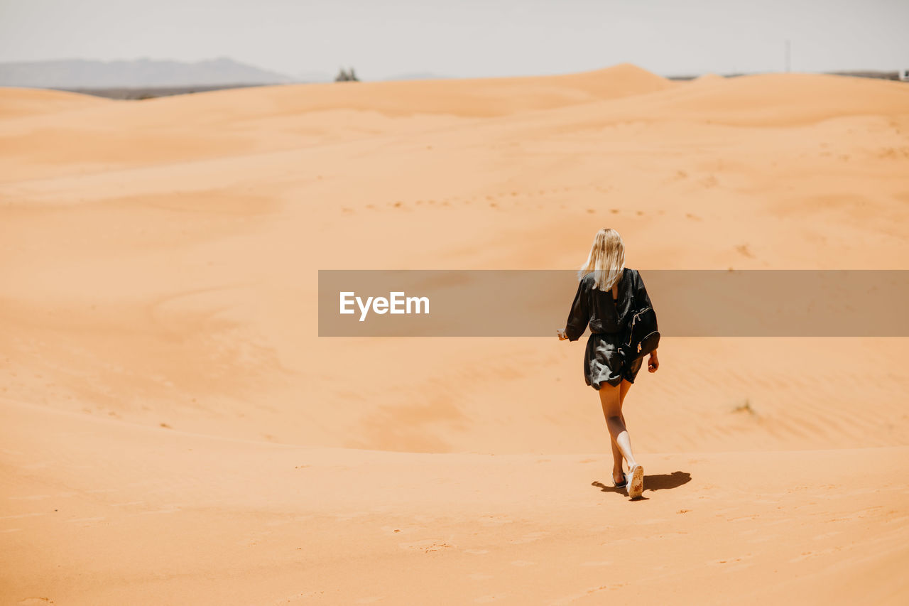 Woman walking on desert in sunny day