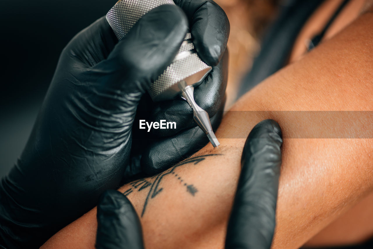 Cropped image of person tattooing on hand